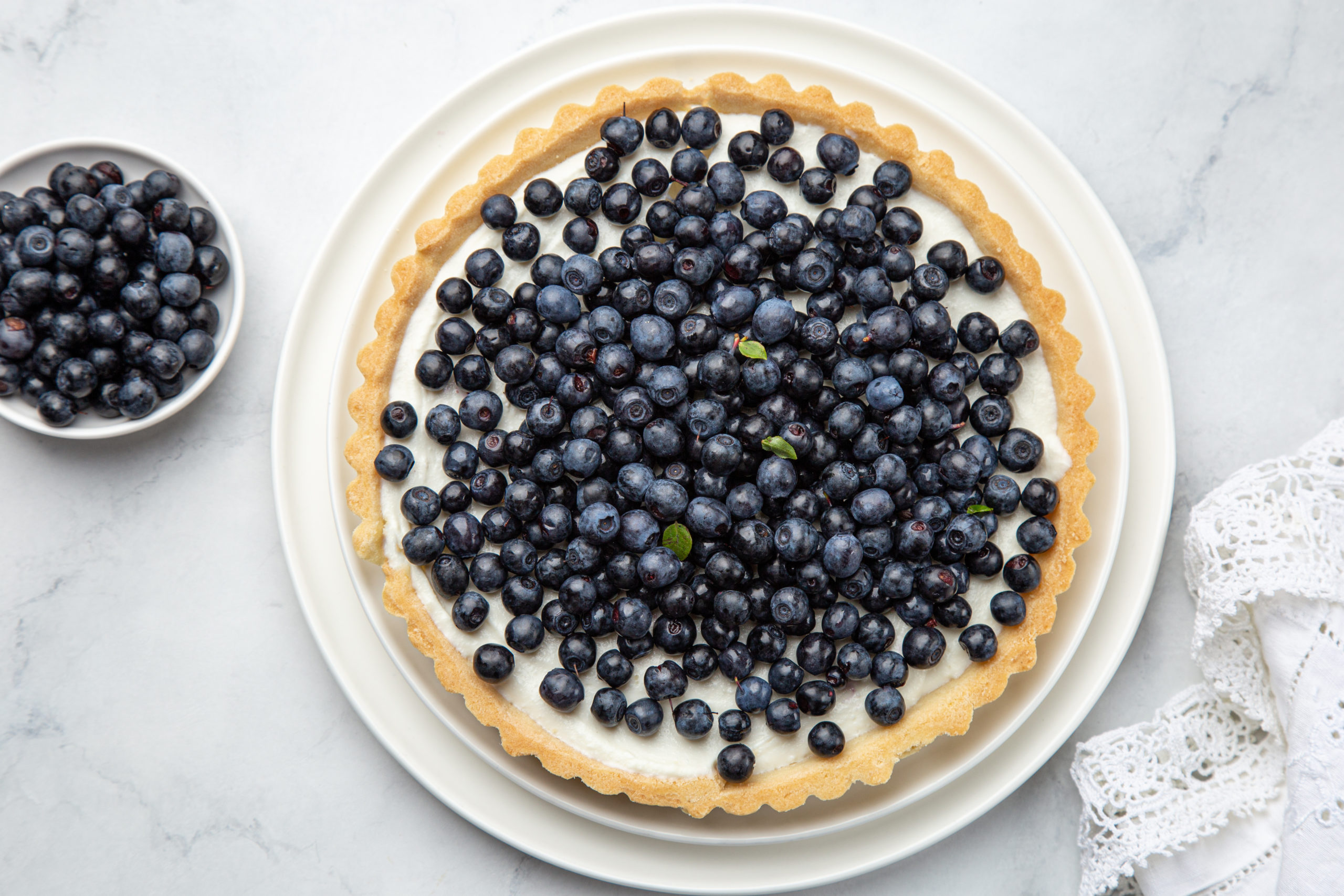 blueberry tart  on white marble background, top view