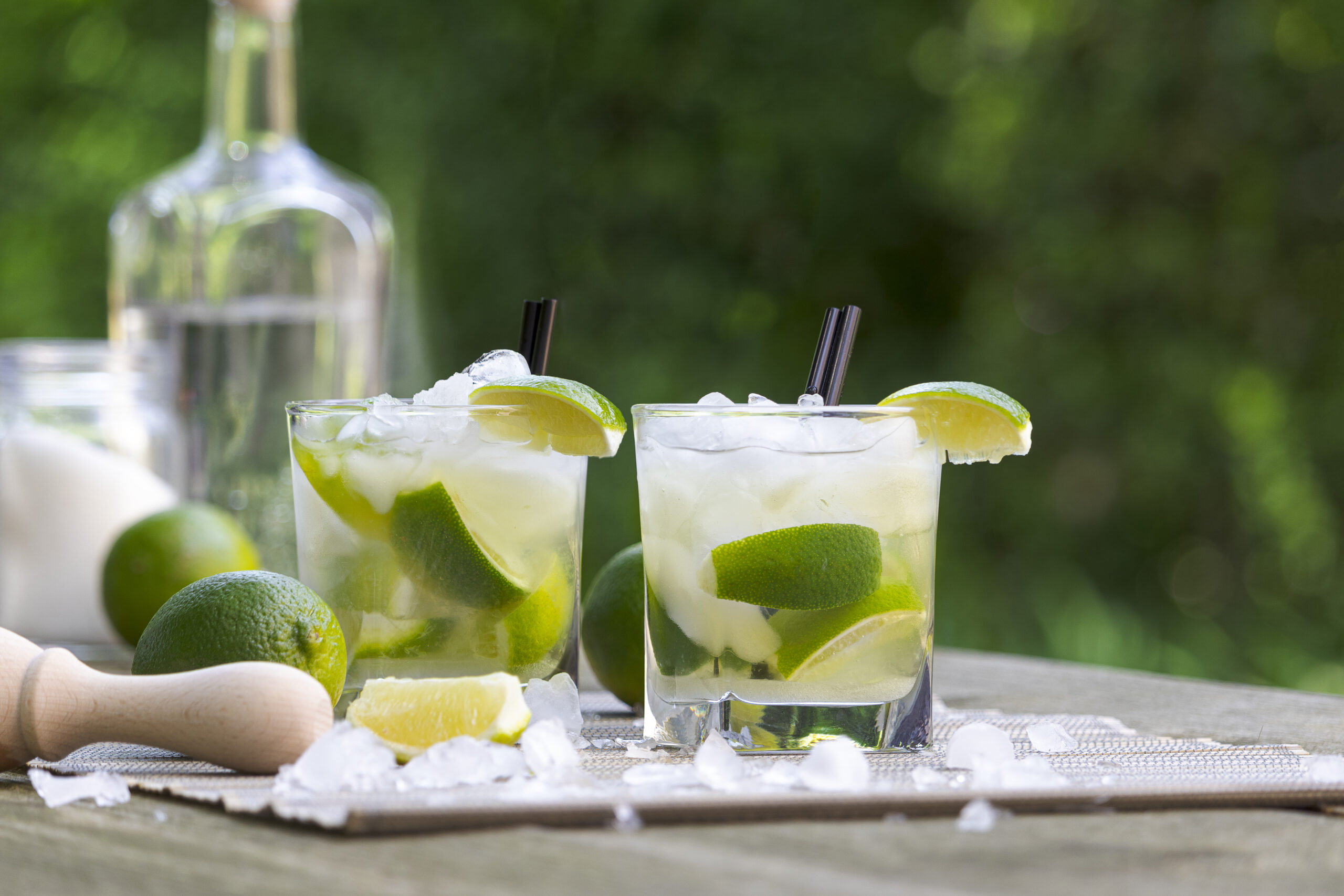 Two delicious fresh Caipirinha drinks with cachaça rum and lime in the garden